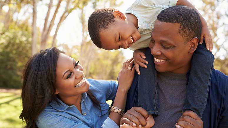 Young family laughing with child on their shoulders