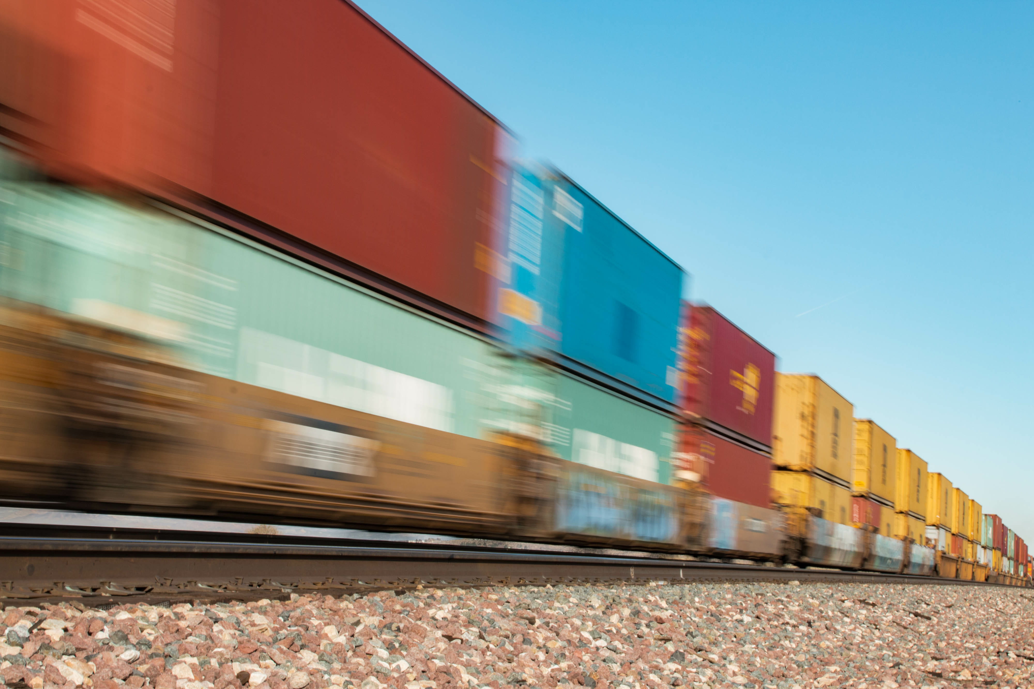 A freight train goes by quickly in a blur.