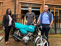 Three people standing by motorbike