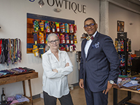 Two people standing in front of a display of bow ties in a store