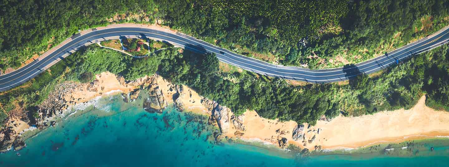 Aerial view of road running a long a beach front through the woods