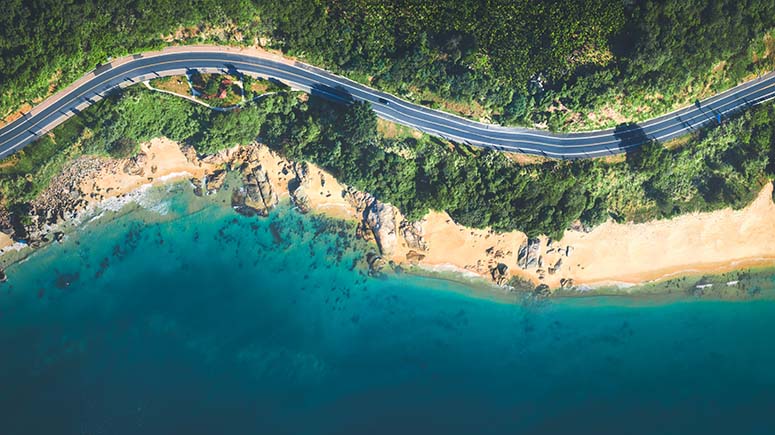 Aerial view of road running a long a beach front through the woods